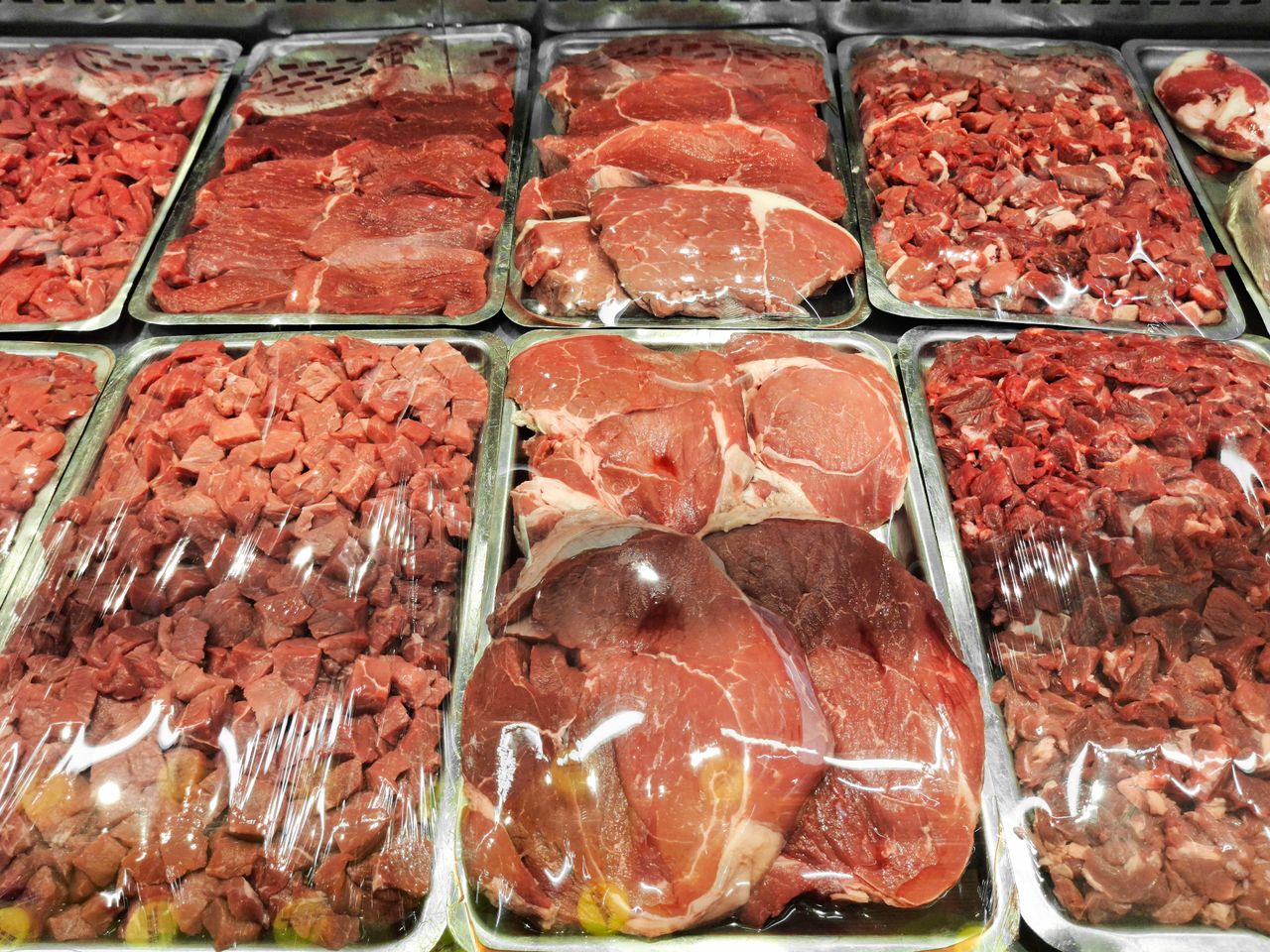 about-img Various cuts of raw meat displayed neatly in a supermarket's refrigerated section.